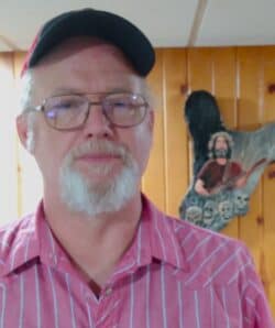 Man in ball cap poses with Jerry Garcia clock in background